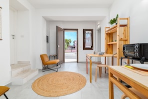 A modern interior with a kitchen area, a dining table, a sofa, and a staircase leading to an outdoor area.