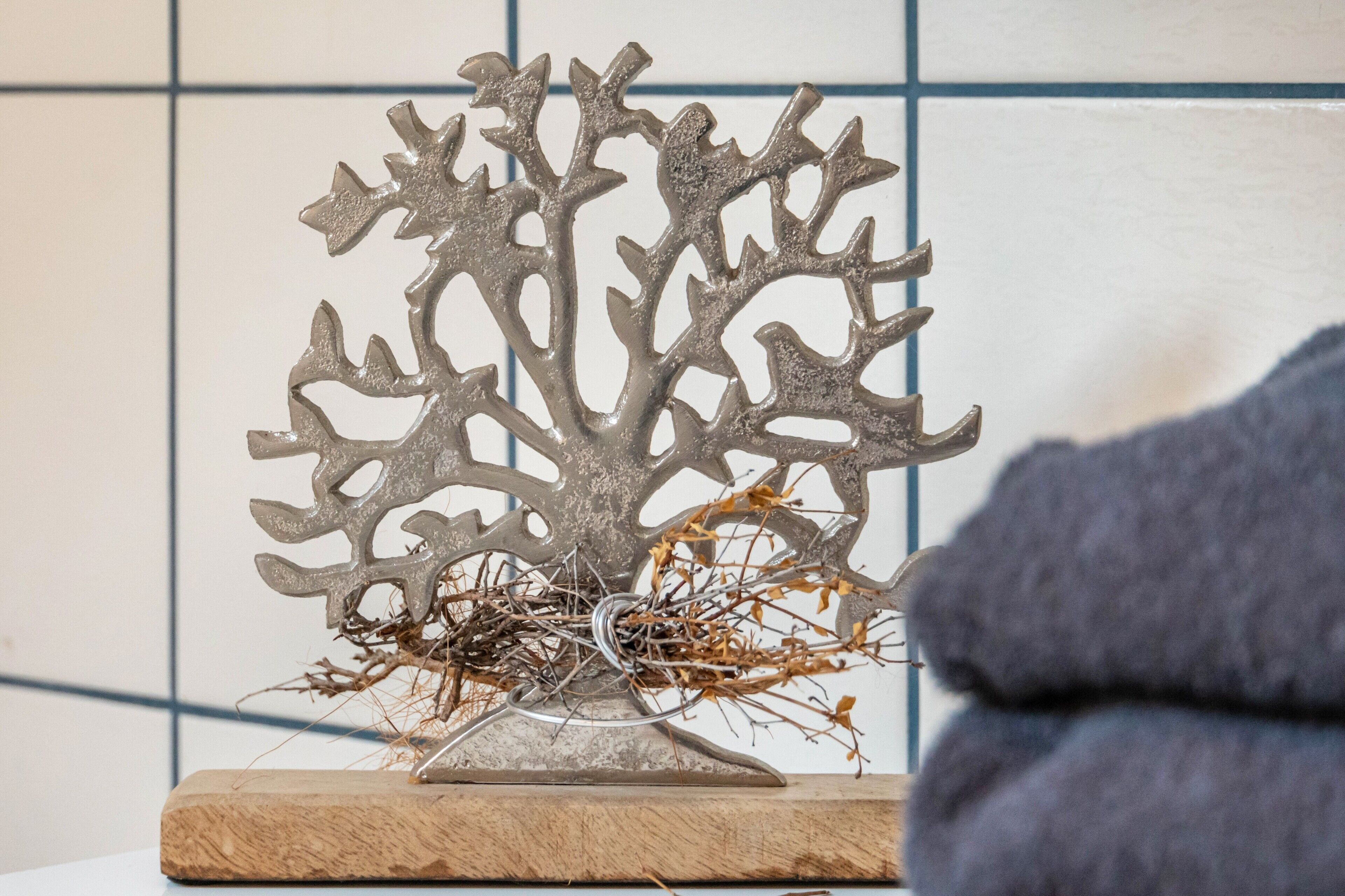 A metal sculpture with a nest on a wooden base.