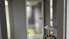 Een kamer met een deur van geëtst glas, een witte muur en een lamp met een gouden voet.