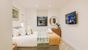Un dormitorio con cama, mesita de noche, cómoda, ventana y obra de arte.