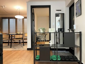 Un interior moderno con comedor, una escalera y un zapatero, junto a una pequeña cocina.
