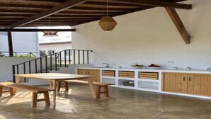 A kitchen with a wooden table and benches, a white countertop, and wooden cabinets.
