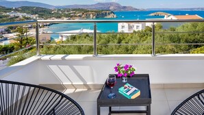 Ein Balkon mit Meerblick, ein Tisch mit einem Buch und einem Glas Rotwein sowie zwei Stühle.