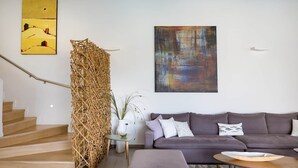 Ein modernes Wohnzimmer mit Treppe, einem grauen Sofa, einem Couchtisch und zwei Kunstwerken an der Wand.