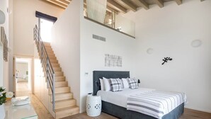 Ein Schlafzimmer mit einem Bett, einer Treppe und Blick ins Freie.