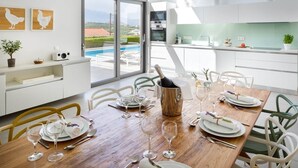 Eine moderne Küche mit Essbereich, großen Fenstern und Blick auf einen Pool.