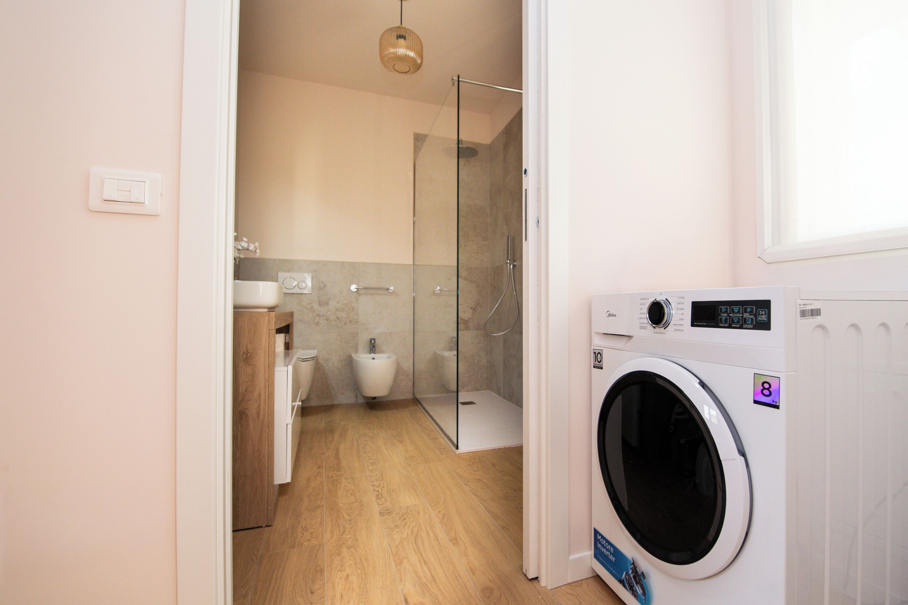 Un baño moderno con cabina de ducha de vidrio, lavadora e inodoro.