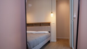 Een slaapkamer met een bed, een houten hoofdeinde, een hanglamp en een houten vloer.