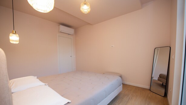 Un dormitorio con una cama, un espejo y una lámpara en el techo.