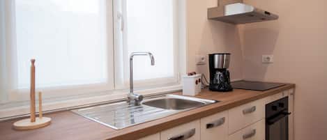 A modern kitchen with a stainless steel sink, a coffee maker, and a built-in oven.