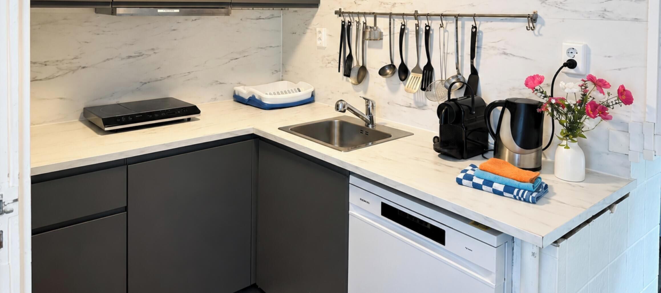 Een moderne keuken met een vaatwasser, waterkoker en koffiezetapparaat.