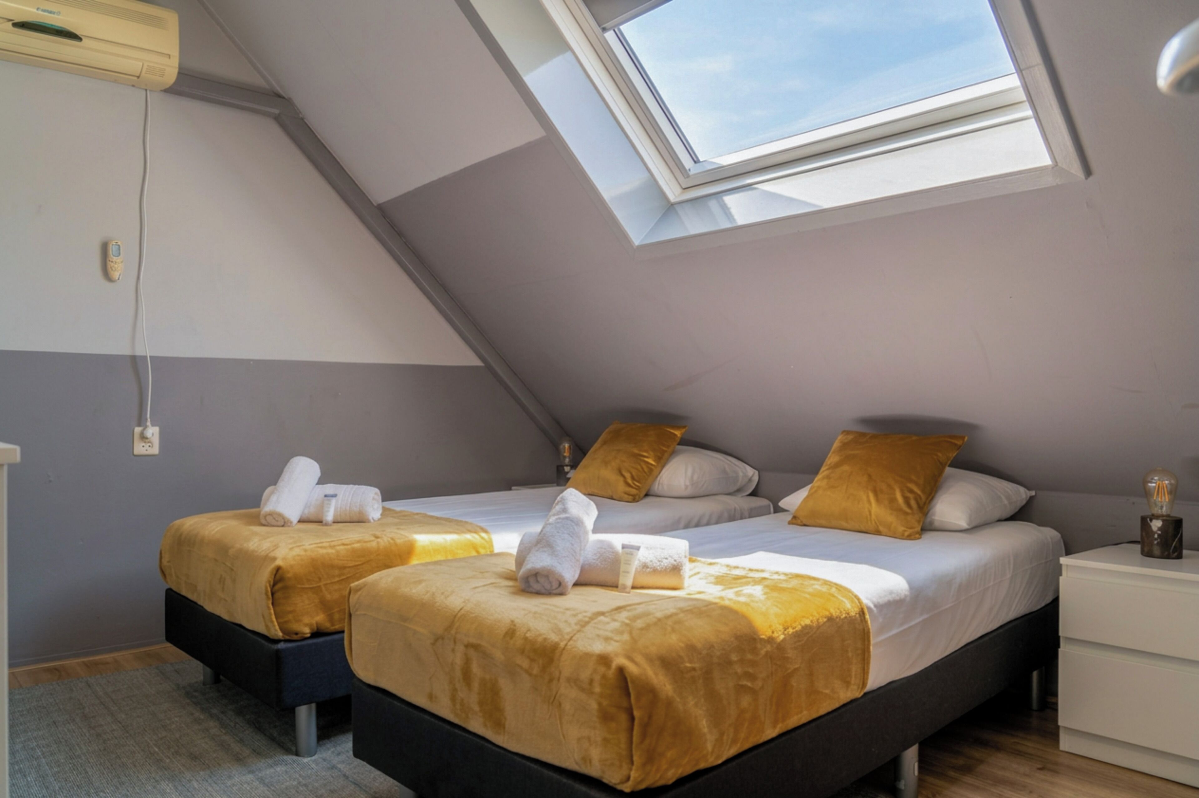 Cozy twin room in a stylish loft space, featuring warm tones, soft lighting, and neatly arranged beds for a comfortable stay.