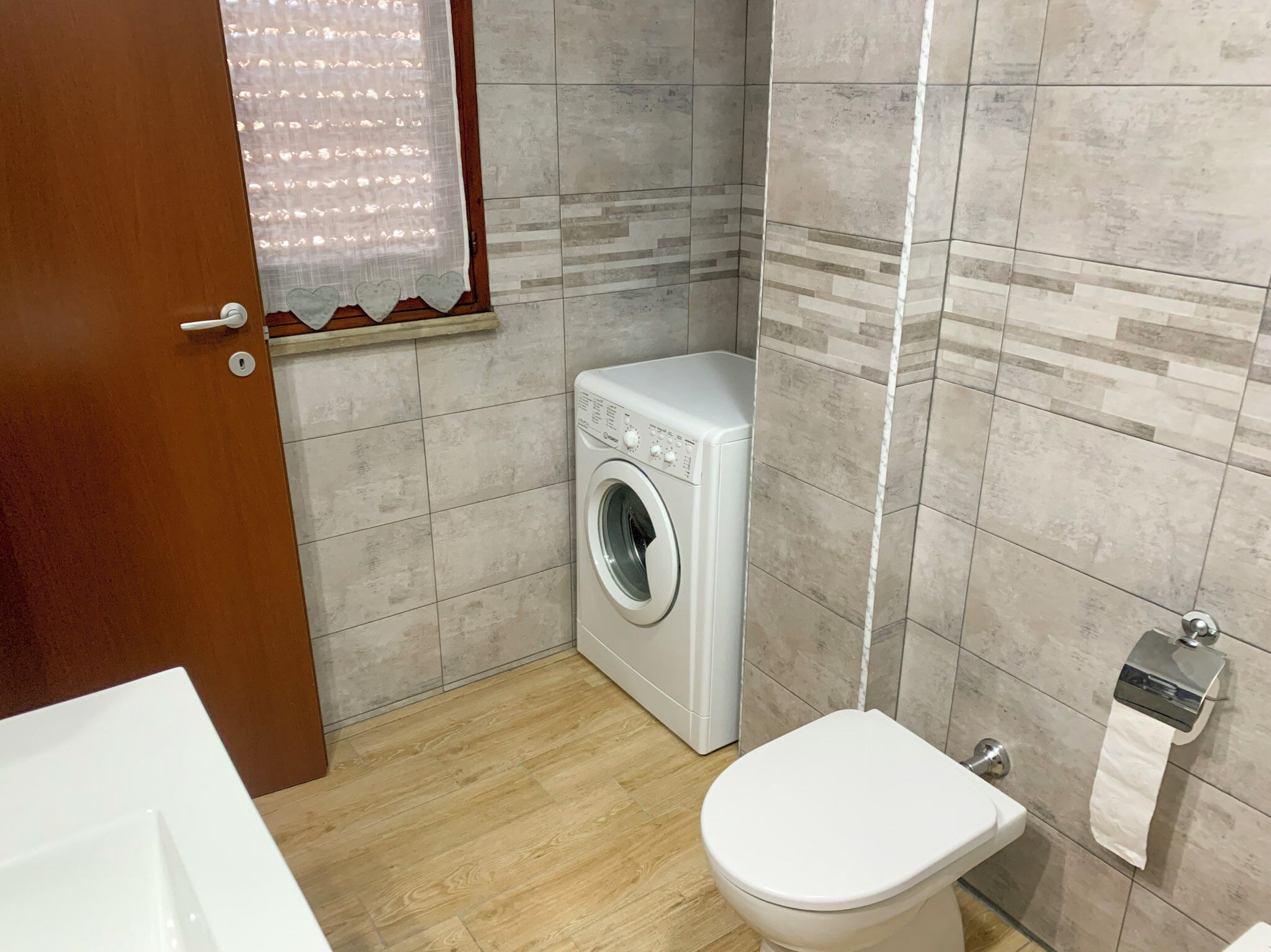 Un baño pequeño con lavadora, inodoro y dispensador de toallas.