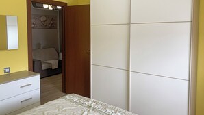 Un dormitorio con cama, armario, espejo y puerta que da a un baño.