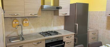 A kitchen with a gas stove, sink, oven, and a refrigerator.