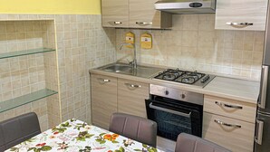 Una cocina compacta con estufa a gas, horno y un comedor con mesa.