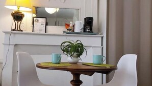 En matplats med ett bord, två stolar, en krukväxt, en kaffebryggare och en lampa.