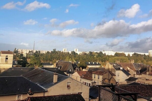 Ein Wohngebiet mit Gebäuden, ein Hügel mit Bäumen und einem klaren Himmel.