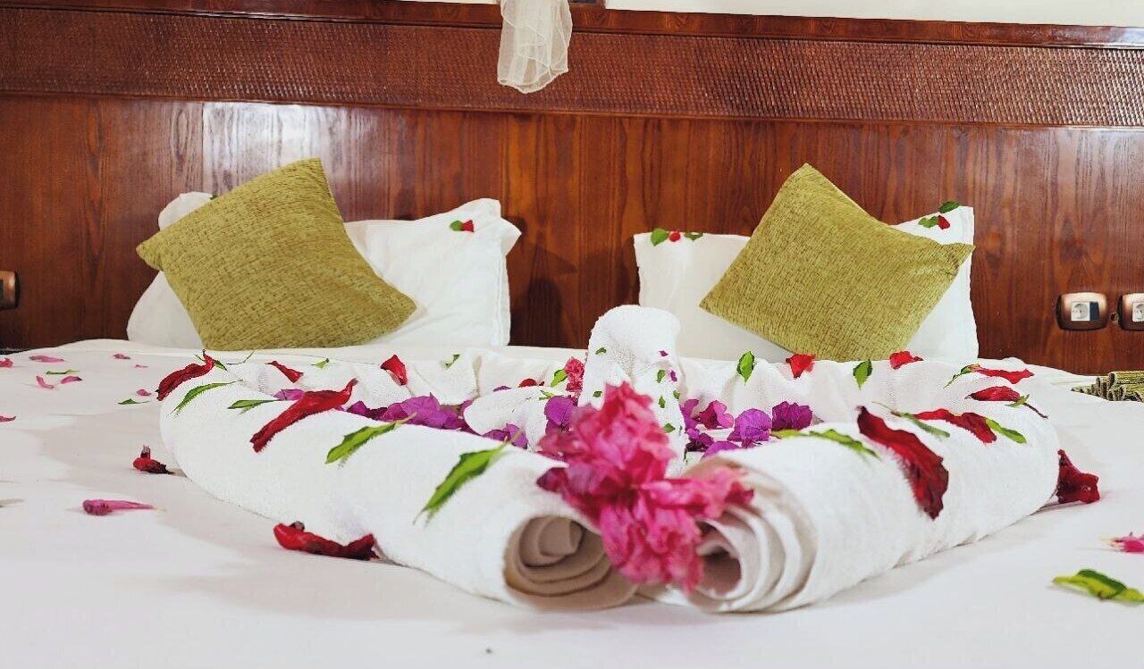 A neatly made bed with floral decorations and a rolled towel.