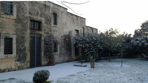 A building with a weathered facade, multiple windows, and potted plants in the courtyard.