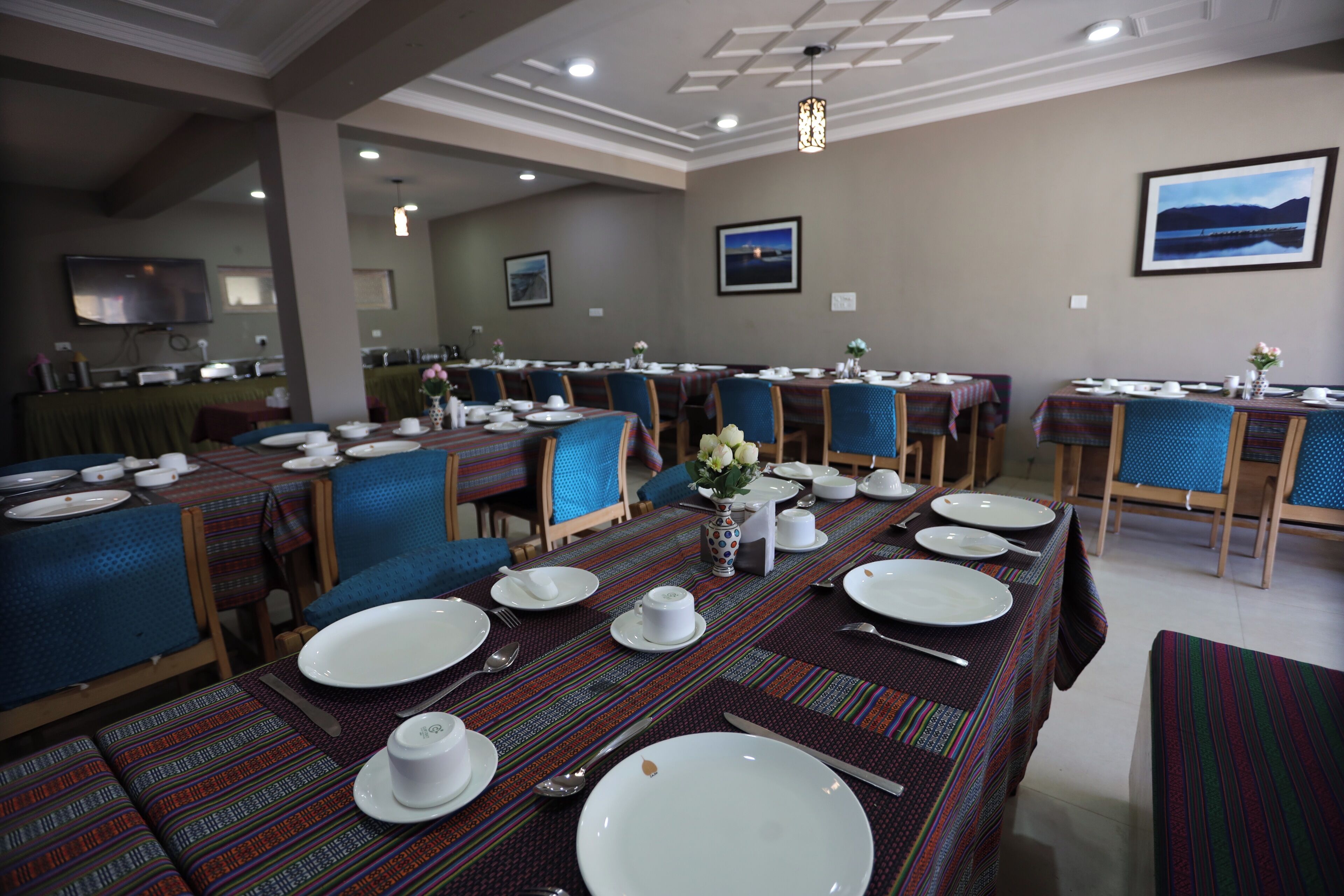 A dining area with tables set for service, chairs, and a television on the wall.