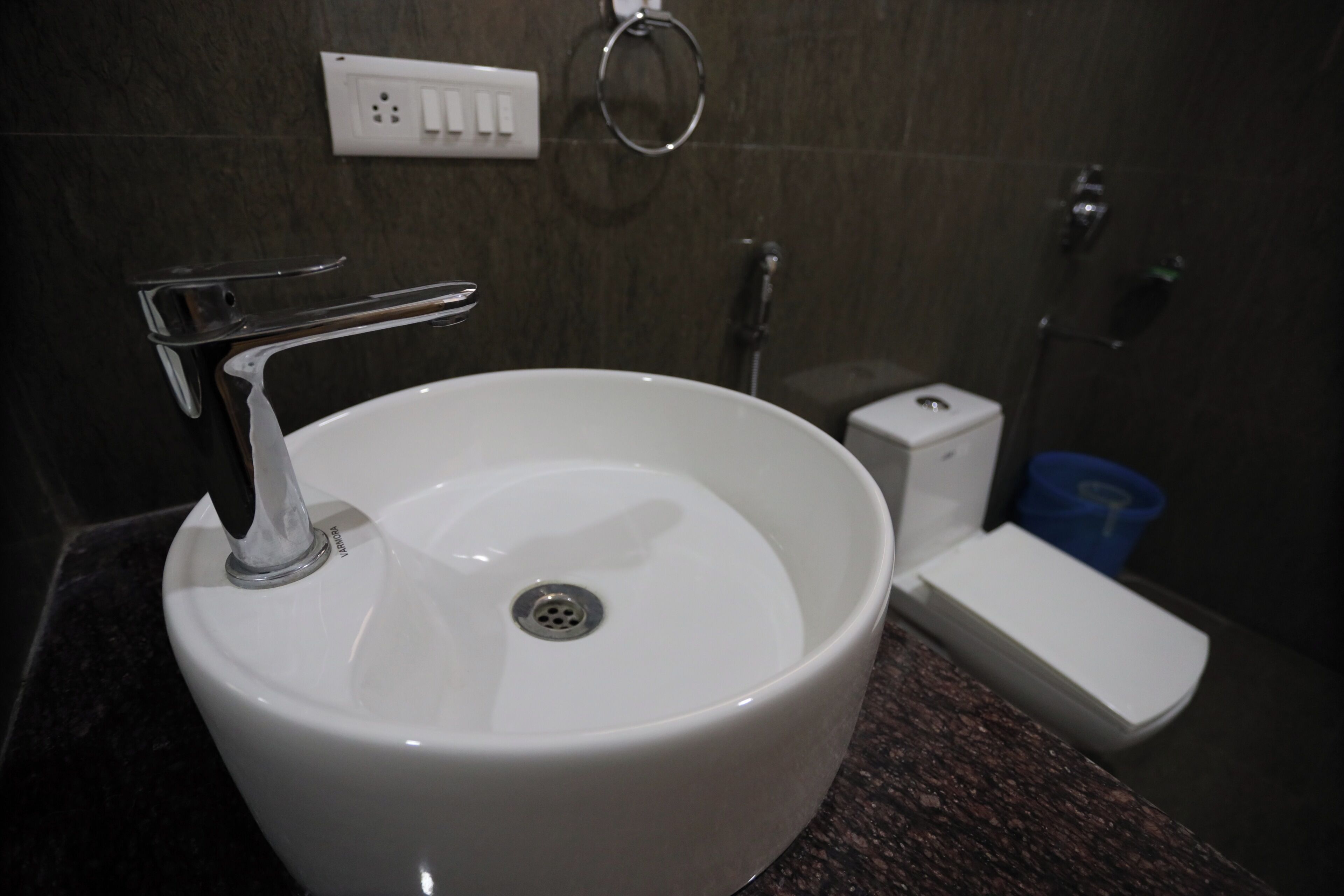A bathroom with a white sink, a faucet, a toilet, and a shower area.
