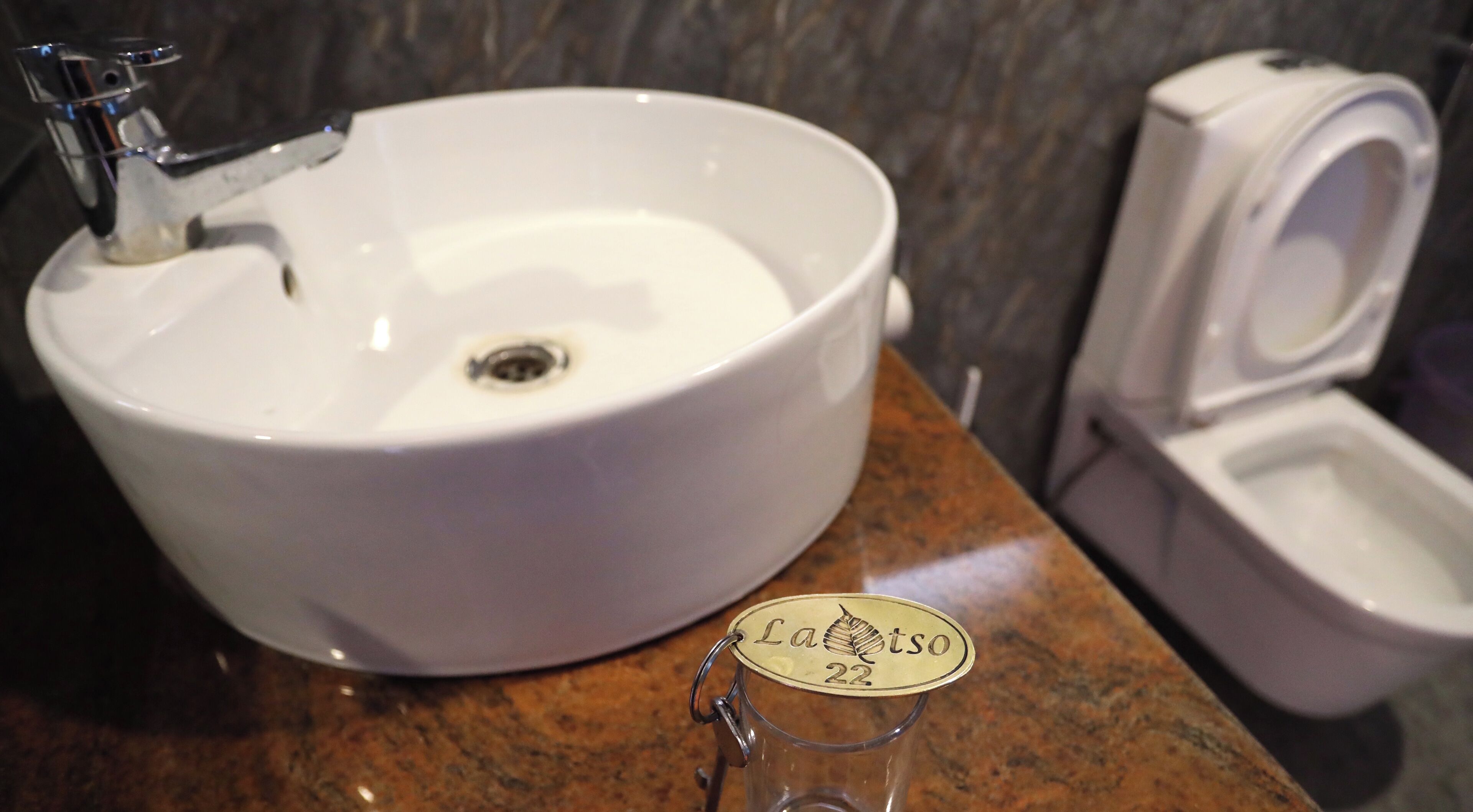 A bathroom with a white sink, a toilet, and a glass jar with a label.