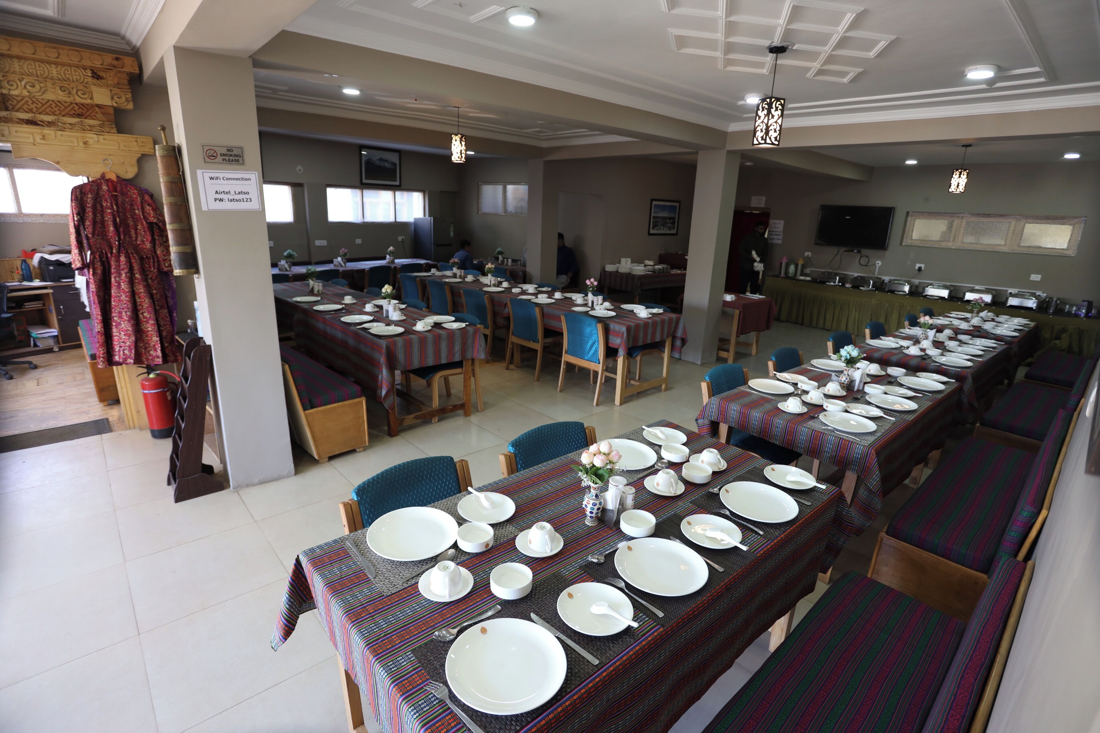 A dining area with tables set for service, a sign indicating WiFi availability, and a television mounted on the wall.