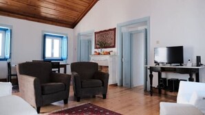A room with a wooden ceiling, two armchairs, a TV, a fireplace, and a table with speakers. - Complete Holiday Home - Herculano, Alexandre and Peregrino (Azóia de Baixo)