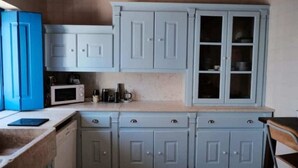 A kitchen with light blue cabinets, a microwave, and a coffee maker on the countertop. - Complete Holiday Home - Herculano, Alexandre and Peregrino (Azóia de Baixo)