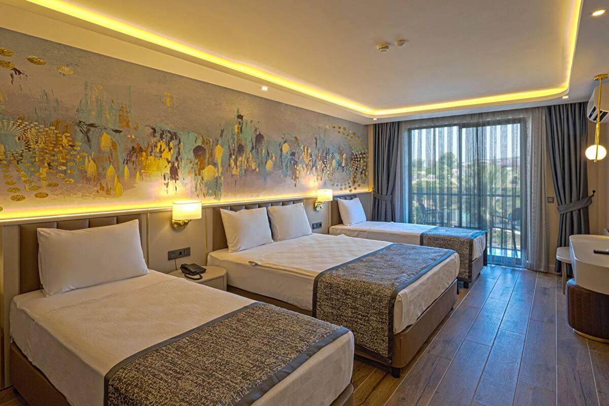 A hotel room with three beds, a large abstract mural, a view through the window, and a modern ceiling design.