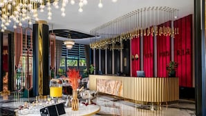 Un espace d’accueil moderne avec un sol en marbre, un comptoir d’accueil et un mur d’accent rouge agrémenté de touches dorées.