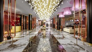 Un hall d’entrée luxueux, doté d’un sol en marbre, de lustres suspendus et d’un élément décoratif central réfléchissant.
