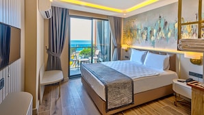 Une chambre d’hôtel avec un grand lit, une télévision, un bureau, une chaise et un balcon avec vue sur la mer.