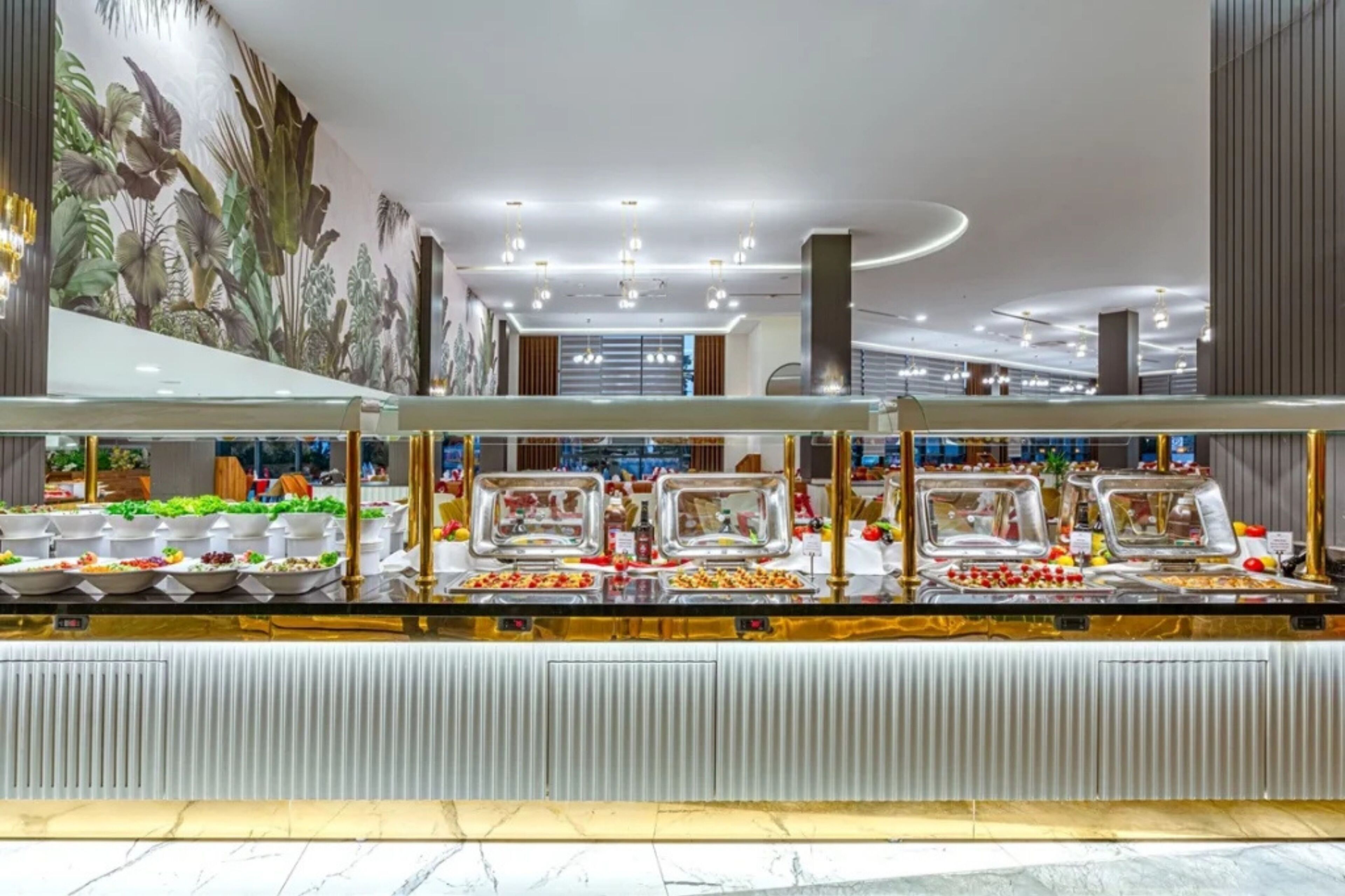 A buffet with various food items and a mural on the wall.