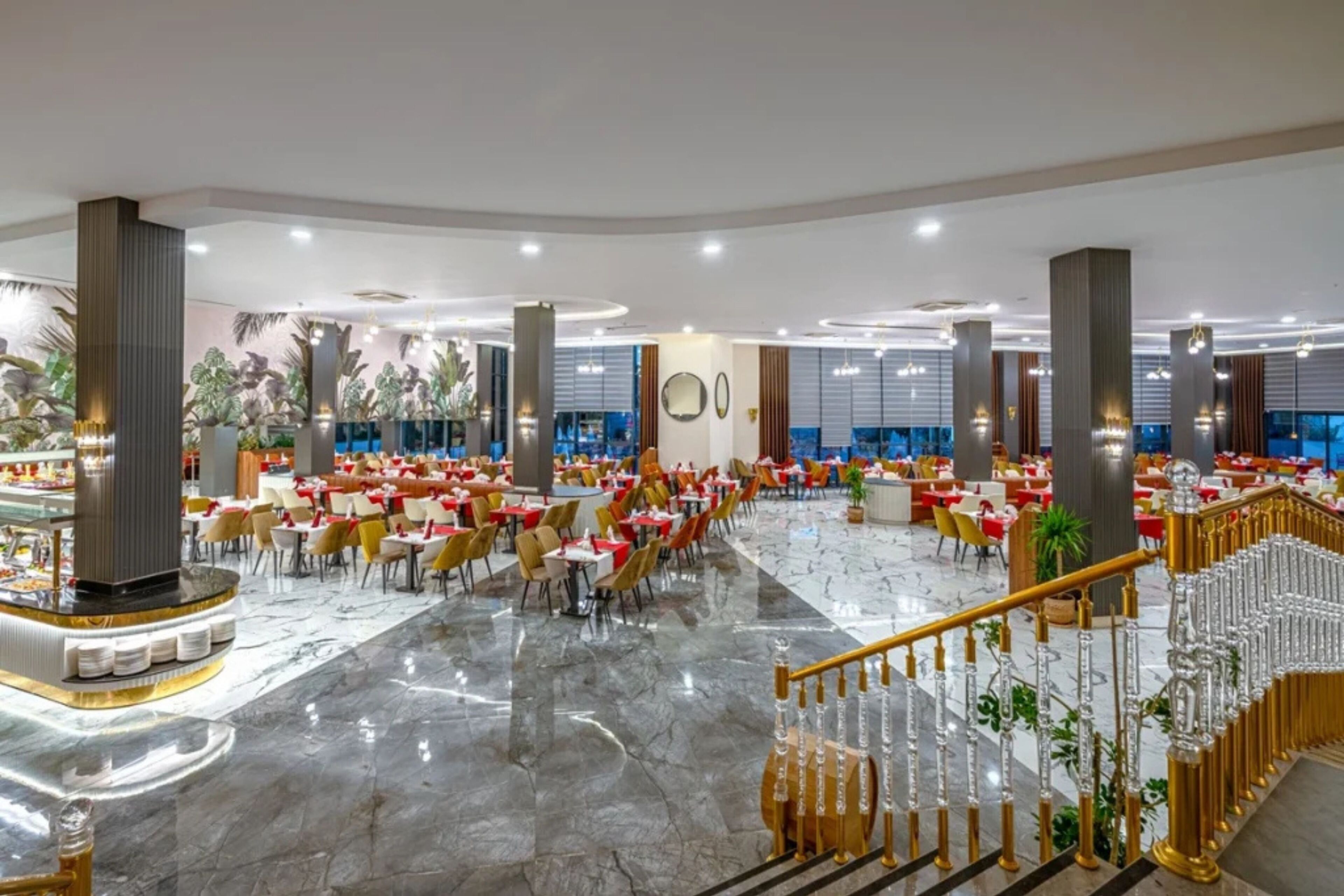 Un amplio vestíbulo de hotel con varias zonas de comedor, una escalera central y un diseño moderno.