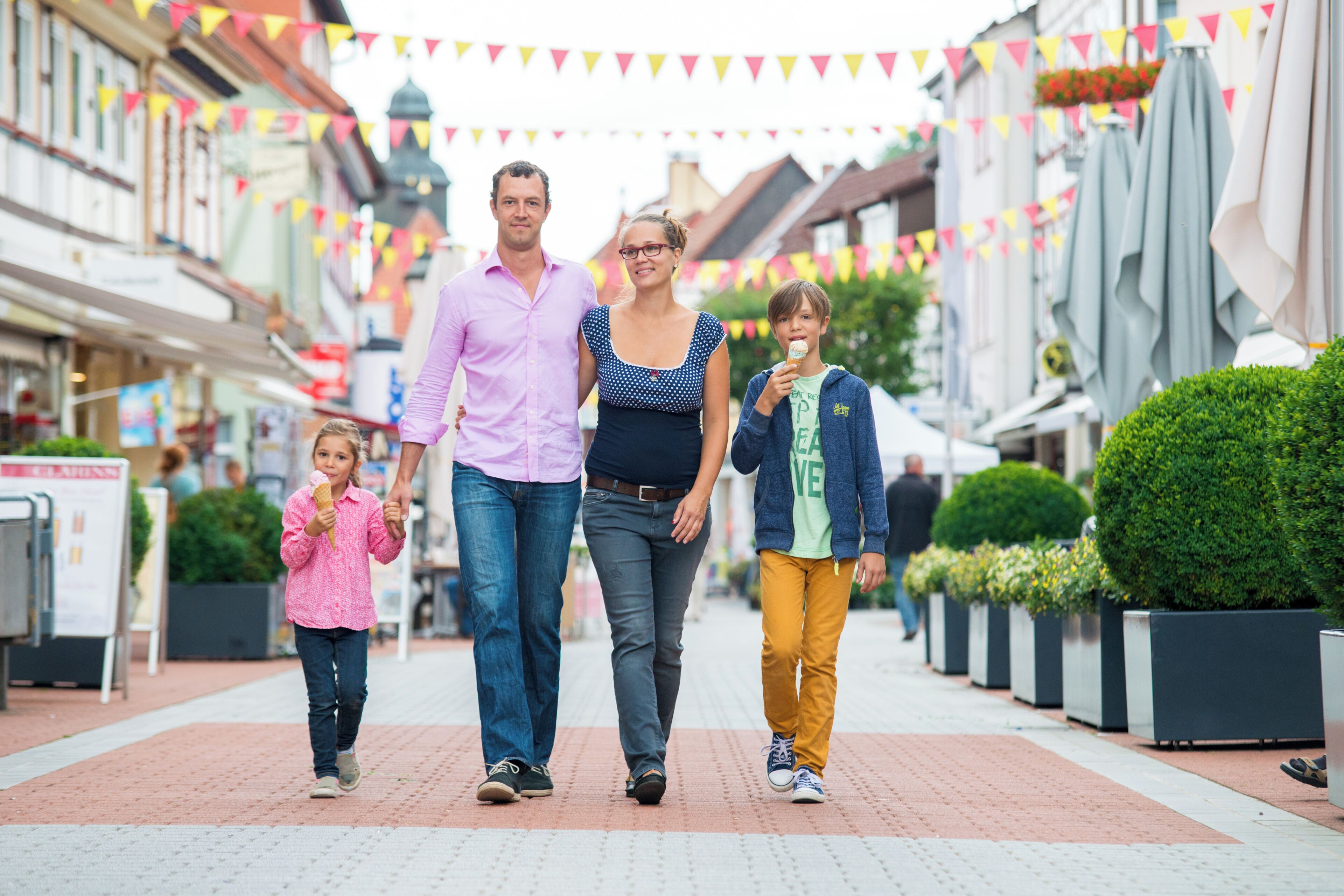 Eine Familie geht auf einer Fußgängerzone zwischen Gebäuden entlang.