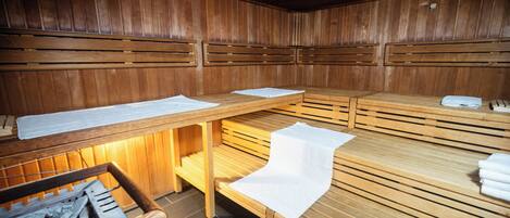 Un sauna avec des bancs en bois, un mur en bois et un banc où sont disposées des serviettes.