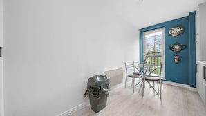 Een keuken met een eettafel en stoelen, een prullenbak en een blauwe accentmuur met decoratieve borden.