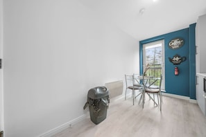 A kitchen with a dining table and chairs, a trash bin, and a blue accent wall with decorative signs.