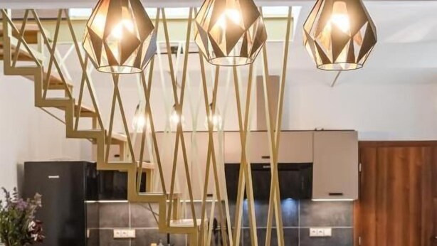 Eine moderne Küche mit Treppe, einer Couch und Pendelleuchten.