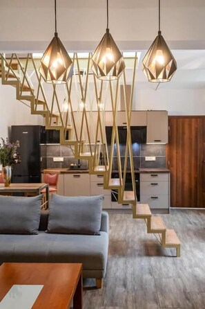 A modern kitchen with a staircase, a sofa, and pendant lights. - Apartmán Všudeblízko 410 (Česká Skalice)