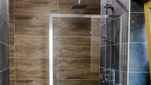Un bagno moderno con cabina doccia in vetro, un water e un lavandino.