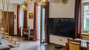 Ein modernes Wohnzimmer mit Flachbildfernseher, einer Holztreppe und einem Essbereich.