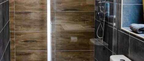 A modern bathroom with a glass-enclosed shower, a toilet, and a sink.