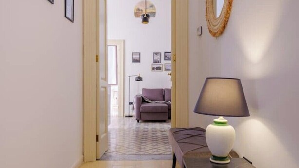 En hall med en lampa, en soffa och en mönstrad matta.