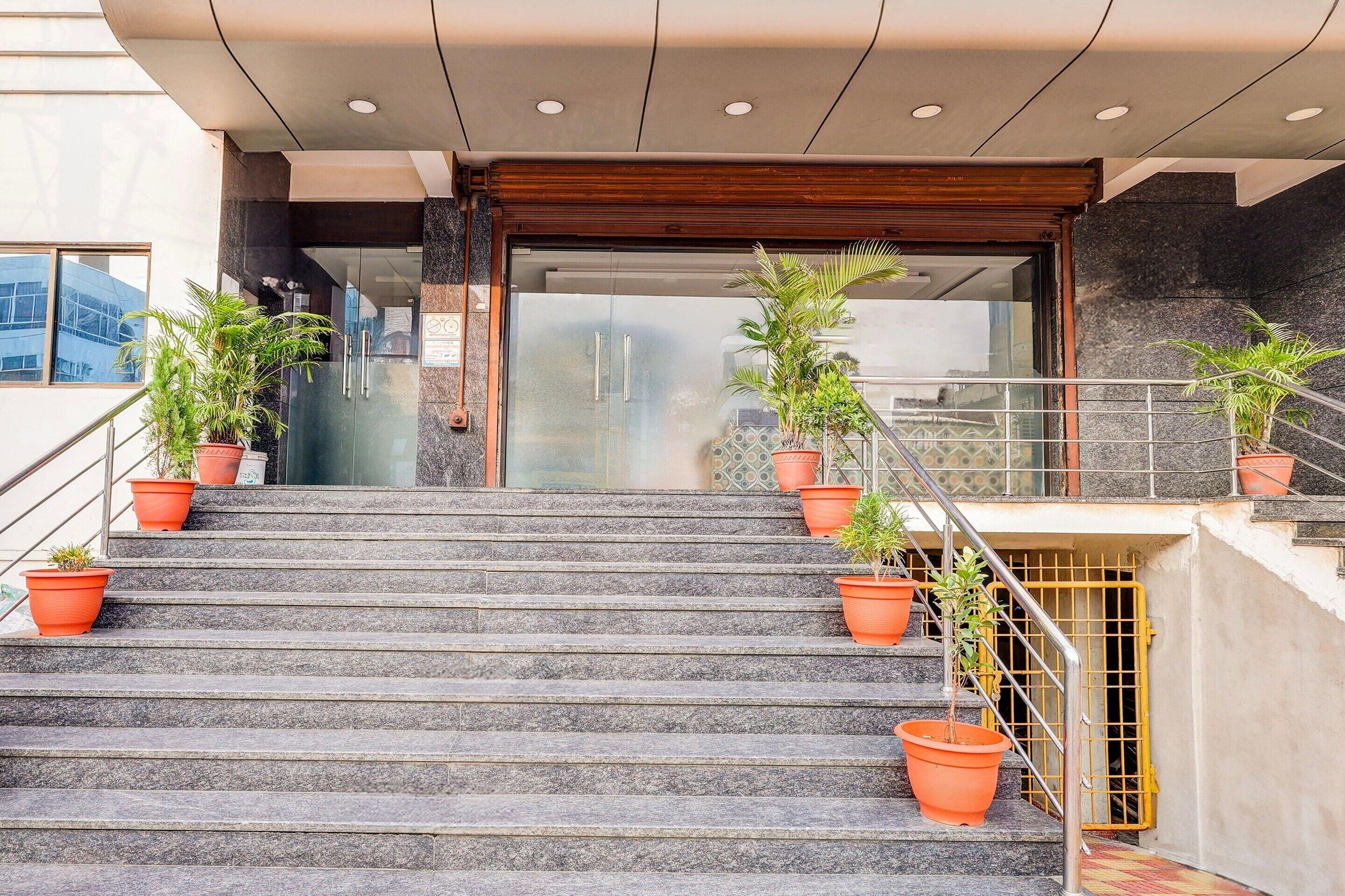 Una escalera con plantas en macetas, un acceso por puerta de cristal y una barandilla de metal.