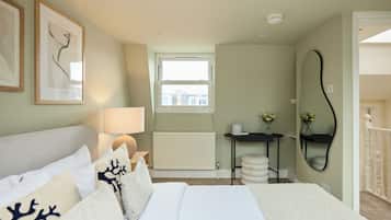 Un dormitorio con cama, mesita de noche, lámpara, radiador, ventana y espejo.