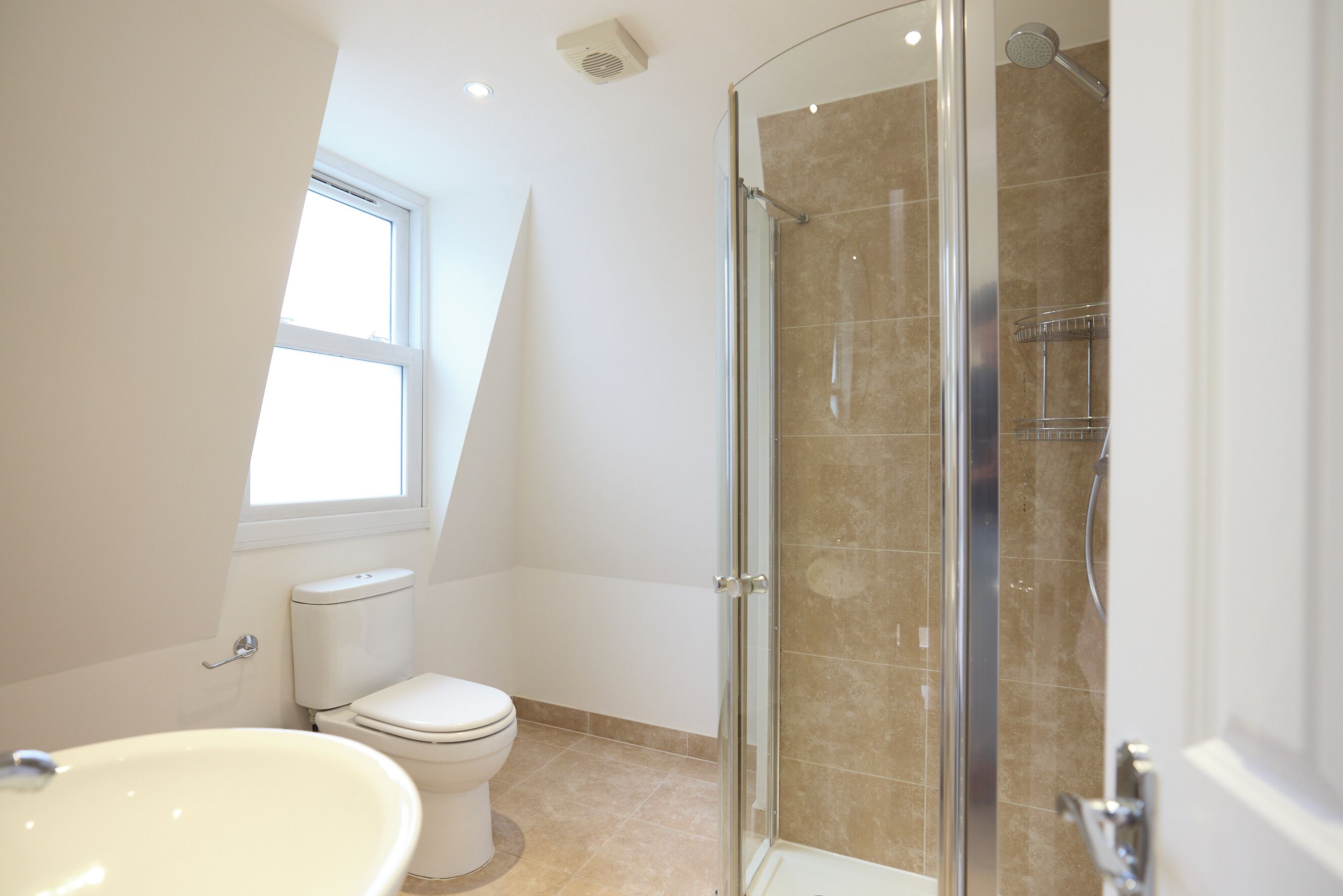 A bathroom with a toilet, sink, and glass-enclosed shower.