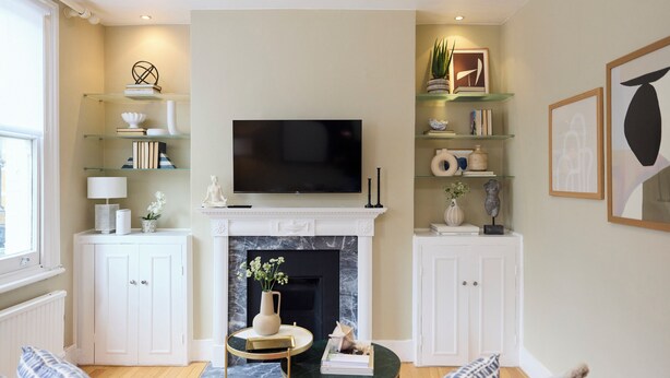 Ein Wohnzimmer mit Kamin, Fernseher und Regalen mit Büchern und Dekoration.
